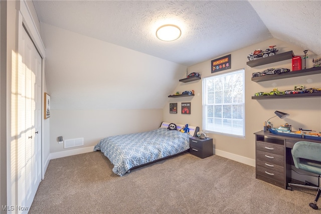 carpeted bedroom with a textured ceiling and vaulted ceiling