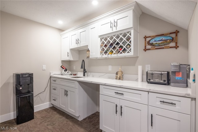 kitchen featuring light stone counters, sink, white cabinets, and a textured ceiling