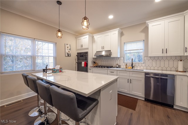 kitchen featuring ornamental molding, white cabinets, sink, appliances with stainless steel finishes, and a center island