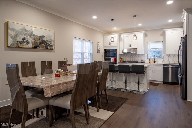 dining space featuring dark hardwood / wood-style flooring, ornamental molding, and sink