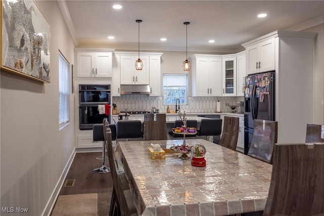 kitchen with dark hardwood / wood-style flooring, crown molding, black appliances, pendant lighting, and a center island