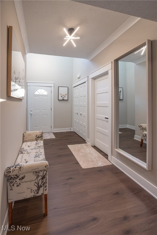 entrance foyer featuring crown molding, dark wood-type flooring, and a textured ceiling