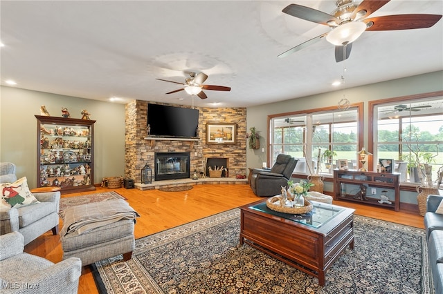 living room featuring ceiling fan, a fireplace, and hardwood / wood-style flooring