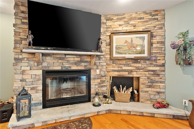 interior details with a stone fireplace and wood-type flooring