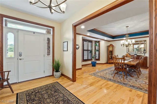 entryway with a chandelier, wood-type flooring, and ornamental molding