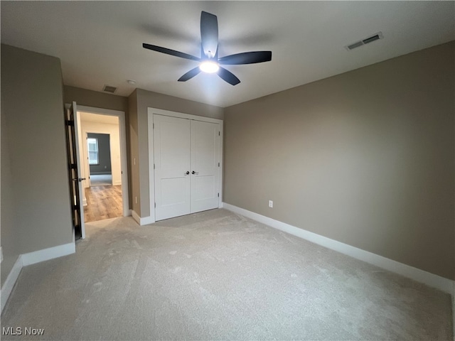 unfurnished bedroom with a closet, ceiling fan, and light carpet