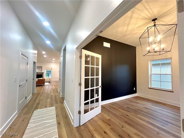 corridor featuring wood-type flooring, vaulted ceiling, and a notable chandelier