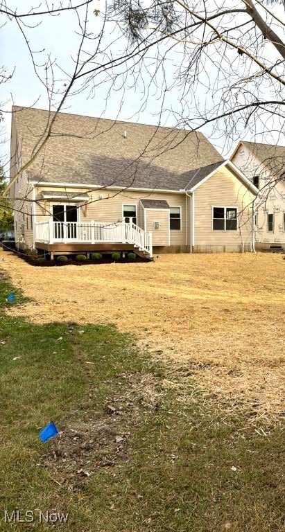 rear view of house featuring a yard and a deck