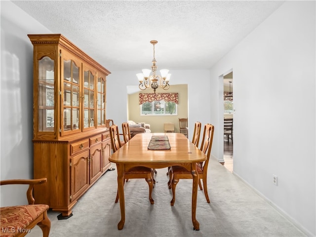 carpeted dining room with a notable chandelier and a textured ceiling