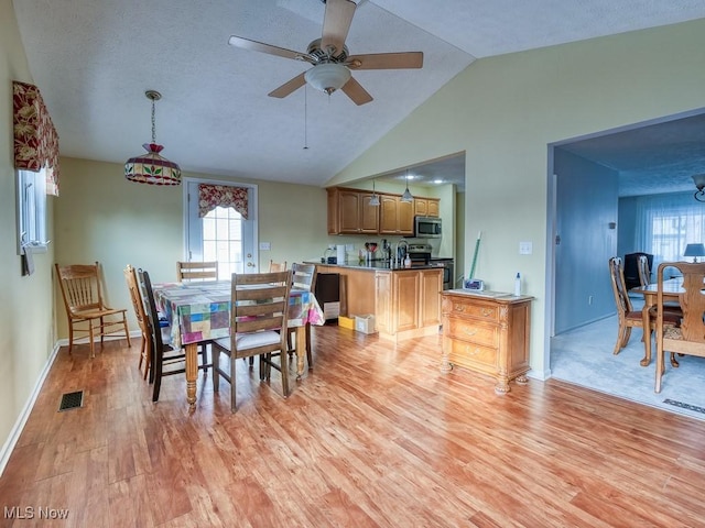 dining area with light wood-type flooring, vaulted ceiling, and a wealth of natural light