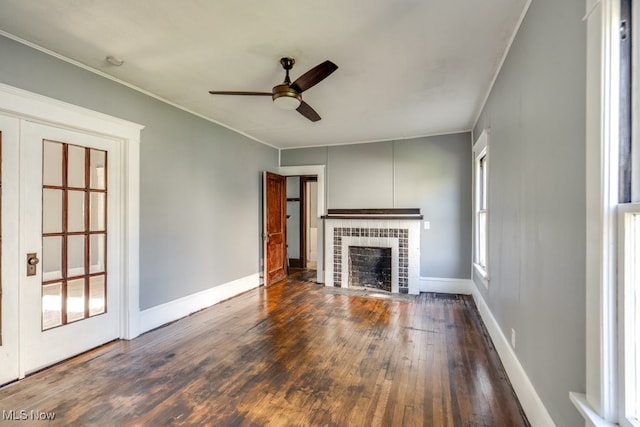 unfurnished living room with a tiled fireplace, a wealth of natural light, dark hardwood / wood-style flooring, and ceiling fan