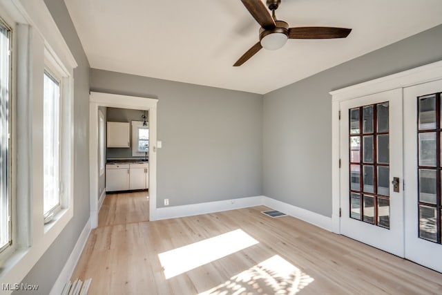 unfurnished room featuring french doors, light hardwood / wood-style flooring, and ceiling fan