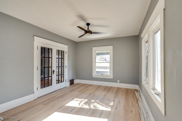 unfurnished room with french doors, baseboard heating, light hardwood / wood-style flooring, and ceiling fan