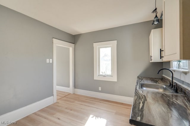 kitchen with white cabinetry, sink, and light wood-type flooring