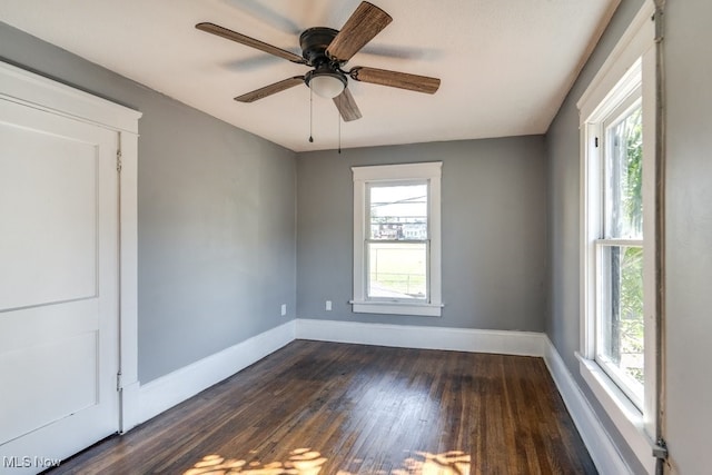 spare room with dark hardwood / wood-style flooring, ceiling fan, and a healthy amount of sunlight