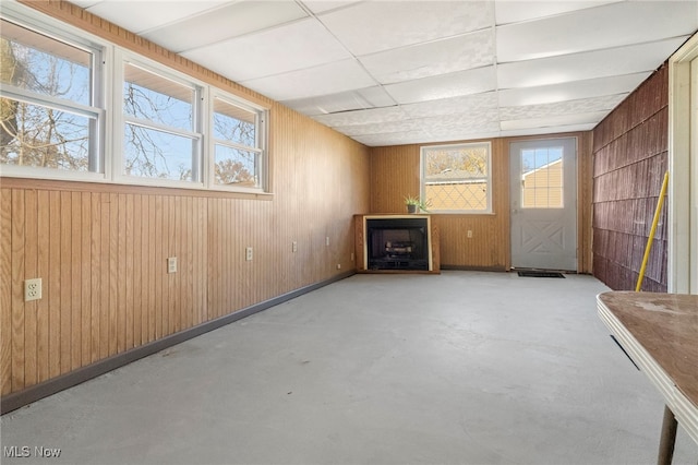 interior space featuring a drop ceiling and wooden walls