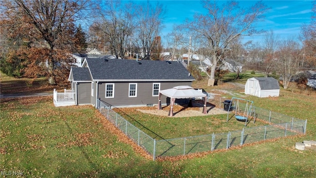 rear view of property with a gazebo, a lawn, and a storage unit