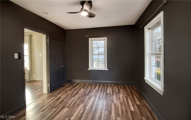 empty room featuring plenty of natural light, dark wood-type flooring, and ceiling fan