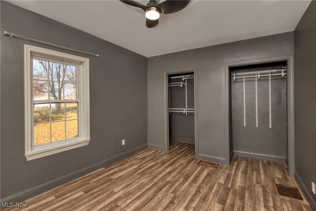 unfurnished bedroom with ceiling fan and dark wood-type flooring