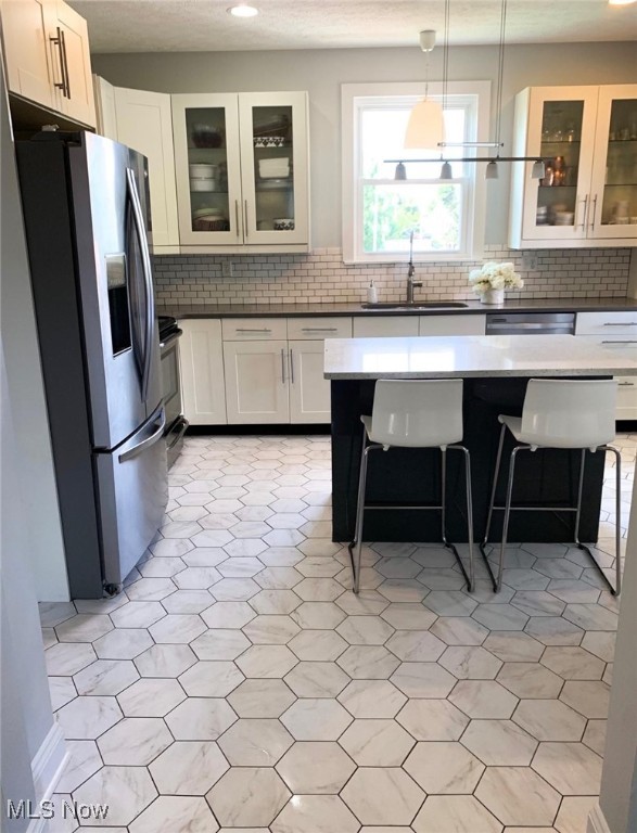 kitchen with a breakfast bar area, white cabinetry, sink, and appliances with stainless steel finishes