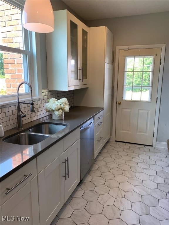 kitchen with a healthy amount of sunlight, sink, white cabinets, and stainless steel dishwasher