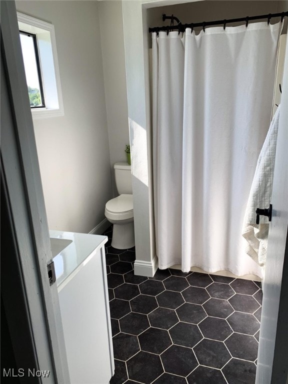 bathroom with curtained shower, vanity, and toilet