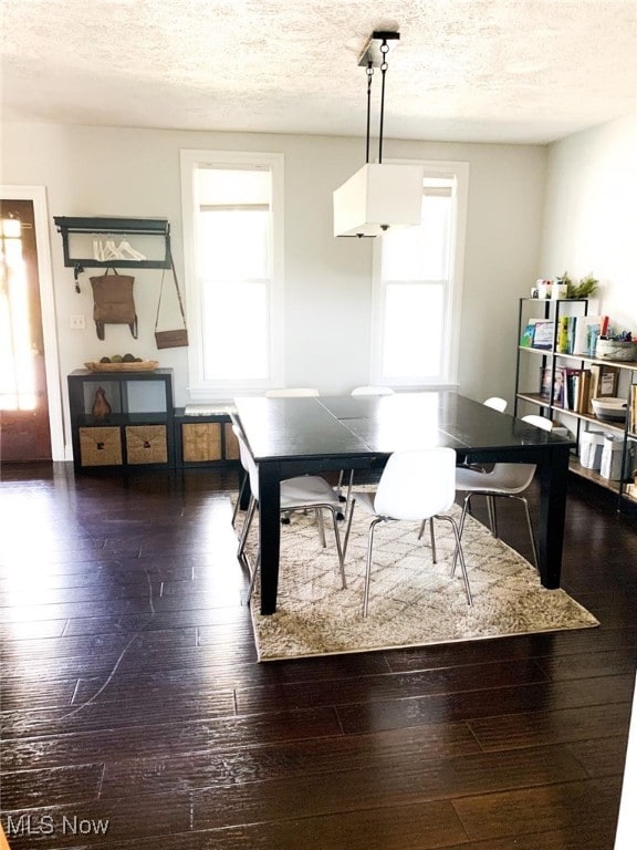 dining space with dark wood-type flooring and a textured ceiling