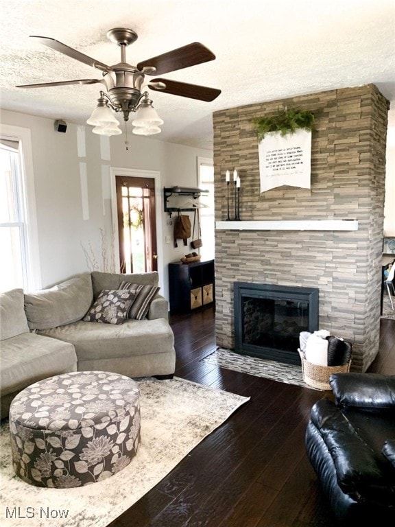 living room with a tile fireplace, dark hardwood / wood-style floors, a wealth of natural light, and ceiling fan