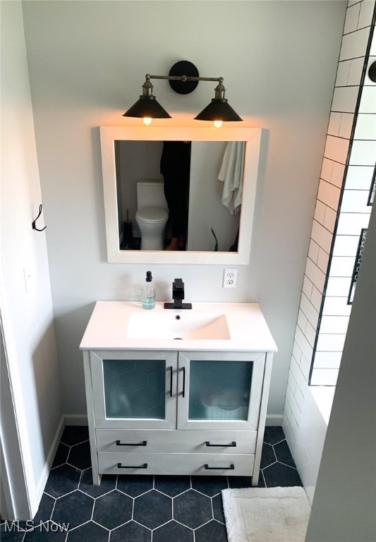 bathroom with toilet, vanity, and tile patterned floors