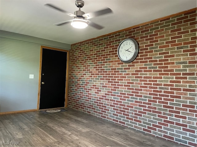 interior space with ceiling fan, dark hardwood / wood-style flooring, and brick wall