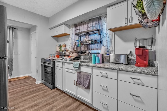 kitchen featuring appliances with stainless steel finishes, a textured ceiling, white cabinets, and light wood-type flooring