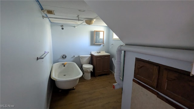 bathroom with a washtub, hardwood / wood-style floors, vanity, and toilet