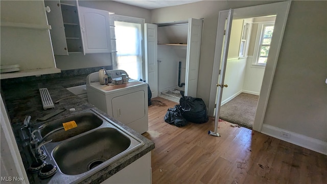 kitchen with washer / clothes dryer, plenty of natural light, white cabinets, and light hardwood / wood-style flooring