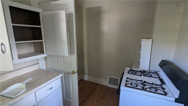 kitchen with dark hardwood / wood-style flooring, white gas range oven, and white cabinetry