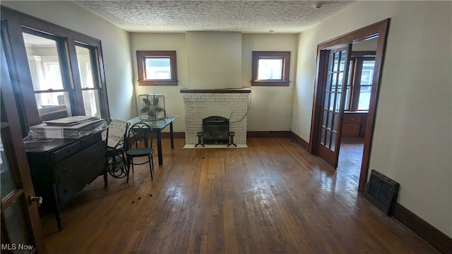 interior space featuring plenty of natural light, dark hardwood / wood-style floors, a textured ceiling, and a brick fireplace