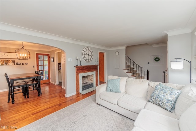 living room with wood-type flooring, ornamental molding, and a notable chandelier