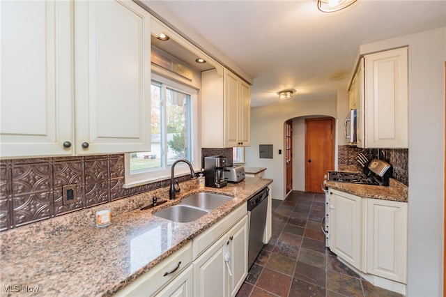 kitchen with backsplash, white cabinets, light stone counters, and sink