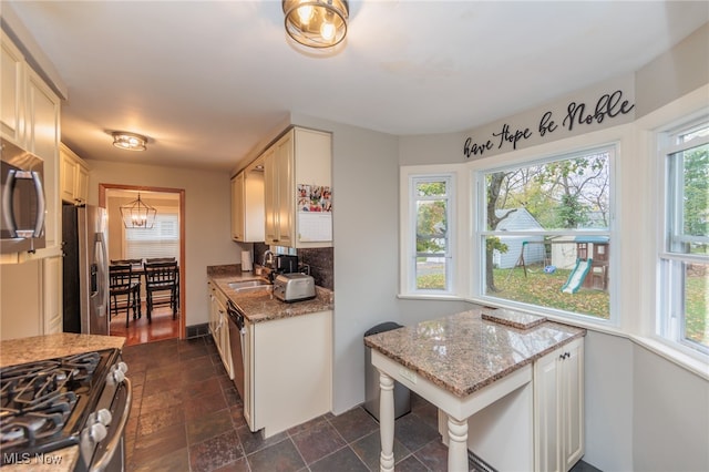 kitchen with a wealth of natural light, sink, light stone countertops, and appliances with stainless steel finishes