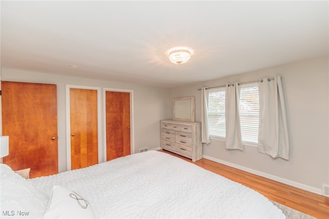 bedroom featuring hardwood / wood-style floors and two closets