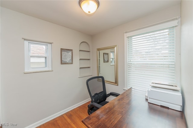 home office with a healthy amount of sunlight and dark hardwood / wood-style flooring