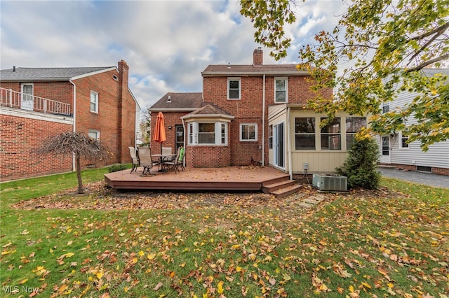 rear view of property featuring a lawn, a wooden deck, and central AC