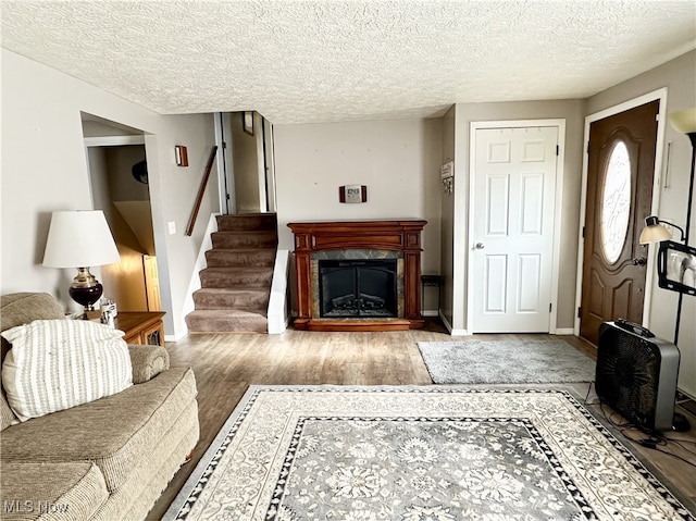 living room featuring a tile fireplace, light hardwood / wood-style floors, and a textured ceiling