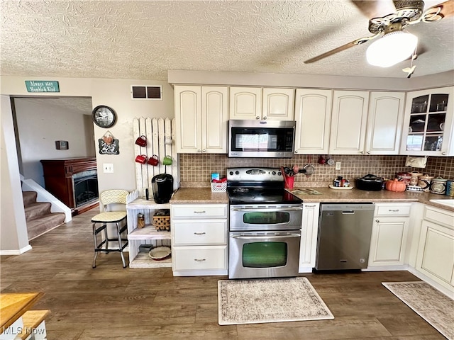 kitchen with appliances with stainless steel finishes, dark hardwood / wood-style flooring, tasteful backsplash, and ceiling fan