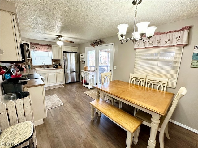 dining area featuring ceiling fan with notable chandelier, a textured ceiling, dark hardwood / wood-style flooring, and sink