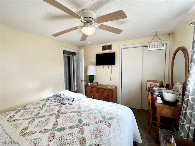 carpeted bedroom with ceiling fan, a closet, and a textured ceiling