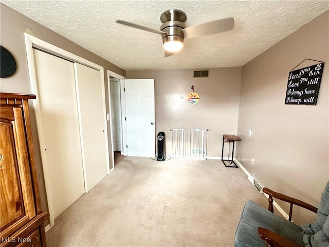 interior space with ceiling fan, light colored carpet, and a textured ceiling