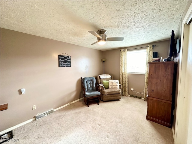 sitting room with a textured ceiling, ceiling fan, and light carpet