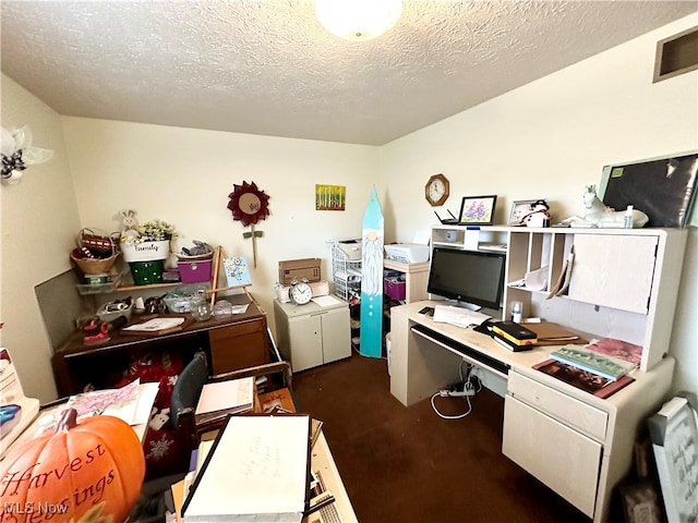 carpeted office space with built in desk and a textured ceiling