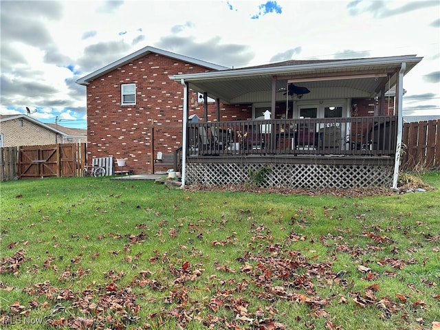 rear view of property featuring a deck, ceiling fan, and a lawn