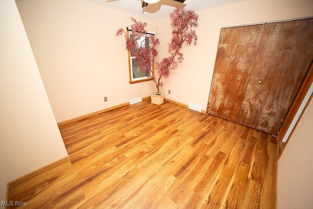 unfurnished bedroom featuring ceiling fan, light hardwood / wood-style floors, and a closet